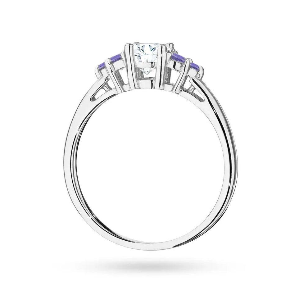 Prsteň z bieleho zlata 14k(585) so 0,60 ct bielym zafírom a 6 tanzanitmi. Je zabalený v elegantnej krabičke, ktorá je ideálna ako darček.