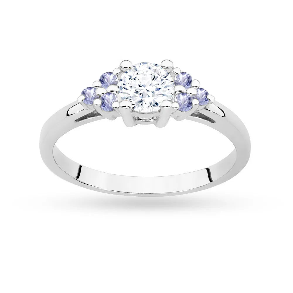 Prsteň z bieleho zlata 14k(585) so 0,60 ct bielym zafírom a 6 tanzanitmi. Je zabalený v elegantnej krabičke, ktorá je ideálna ako darček.