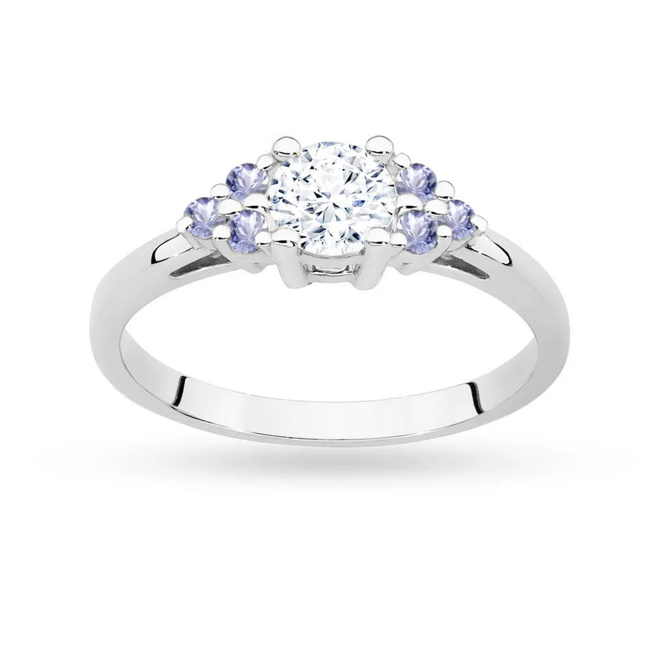 Prsteň z bieleho zlata 14k(585) so 0,60 ct bielym zafírom a 6 tanzanitmi. Je zabalený v elegantnej krabičke, ktorá je ideálna ako darček.