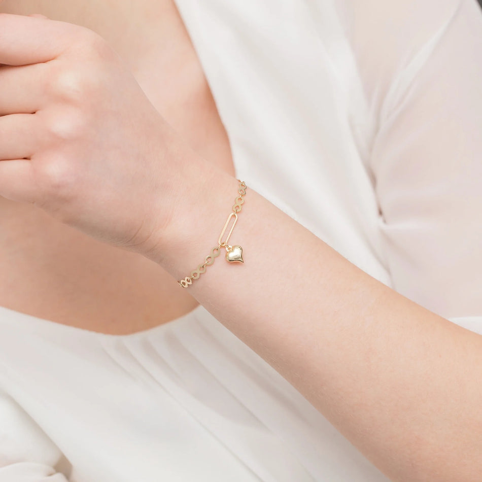 Gold bracelet with infinity symbols, wide links, and a heart charm